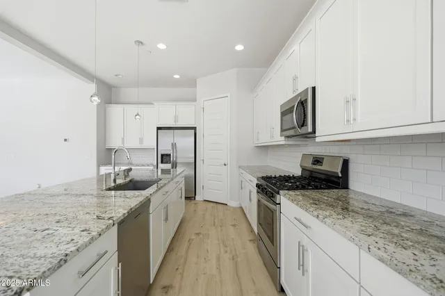 a kitchen with stainless steel appliances granite countertop a sink stove and refrigerator