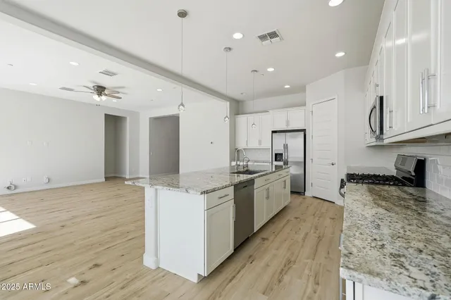 a large kitchen with stainless steel appliances granite countertop a lot of counter space and wooden floors