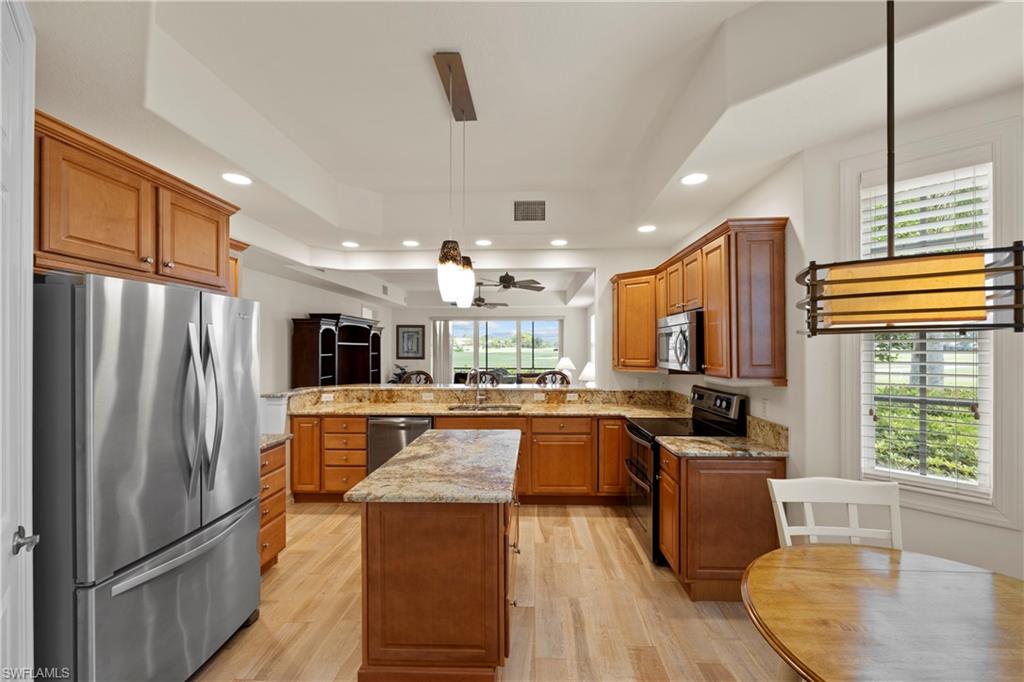 8613 Champions Point, Unit 302 Naples, FL 34113 - Photo 14 of 41 a kitchen with stainless steel appliances granite countertop a refrigerator a stove top oven a sink dishwasher and wooden cabinets with wooden floor