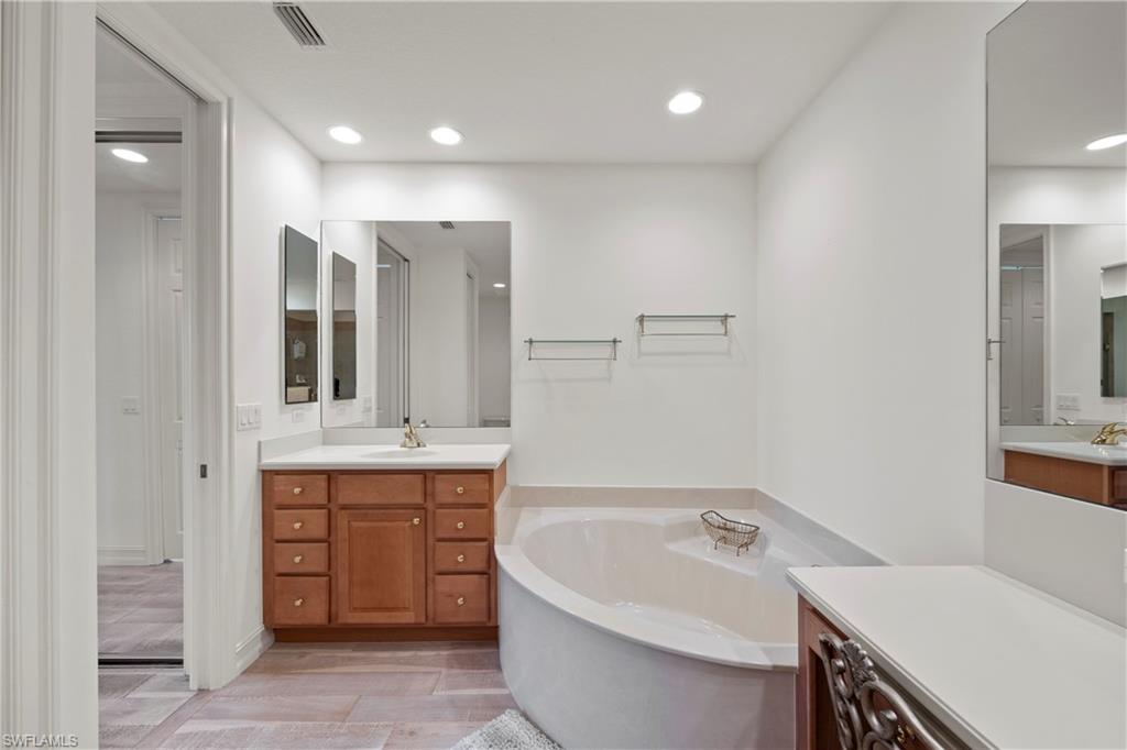 8613 Champions Point, Unit 302 Naples, FL 34113 - Photo 19 of 41 a bathroom with a tub sink and mirror
