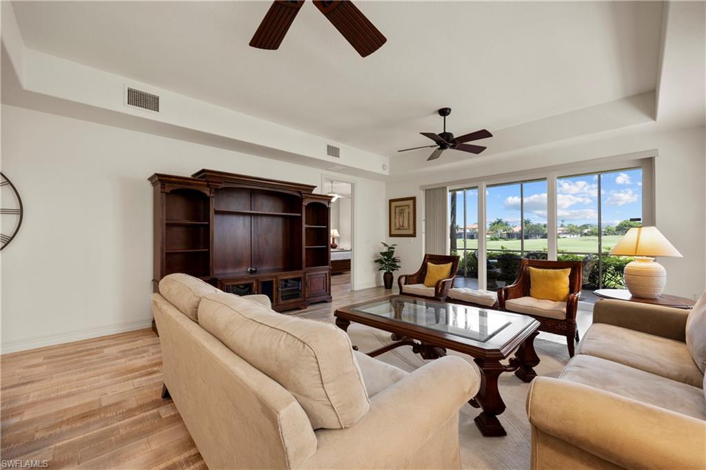 8613 Champions Point, Unit 302 Naples, FL 34113 - Photo 8 of 41 a living room with furniture a ceiling fan and a large window