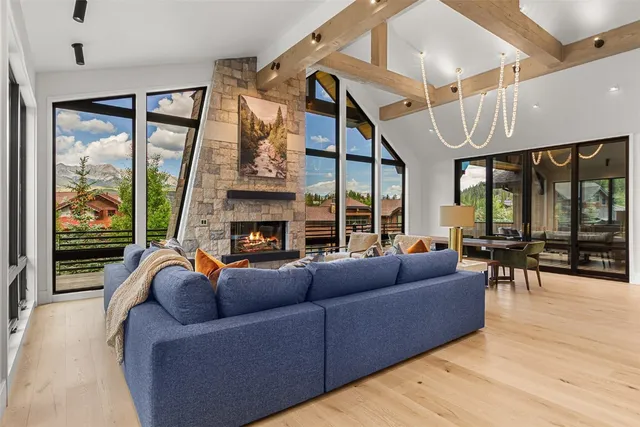 a living room with furniture a fireplace and floor to ceiling windows