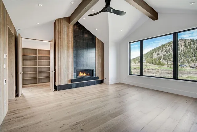 an empty room with wooden floor fan and windows