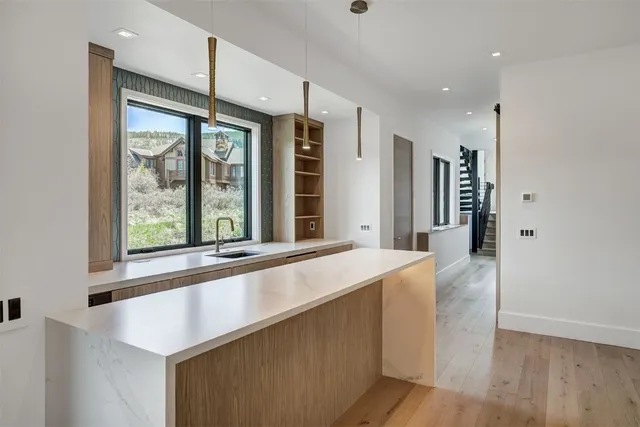 a living room with stainless steel appliances wooden floor and a large window