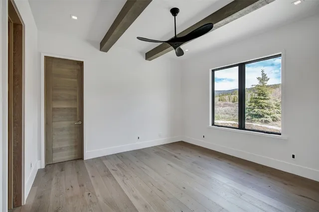 an empty room with wooden floor cabinet and windows