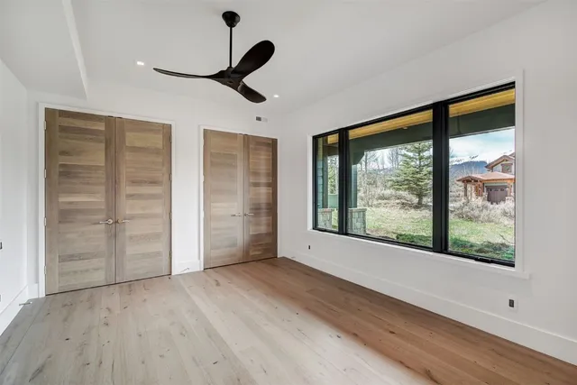 a view of empty room with wooden floor and fan