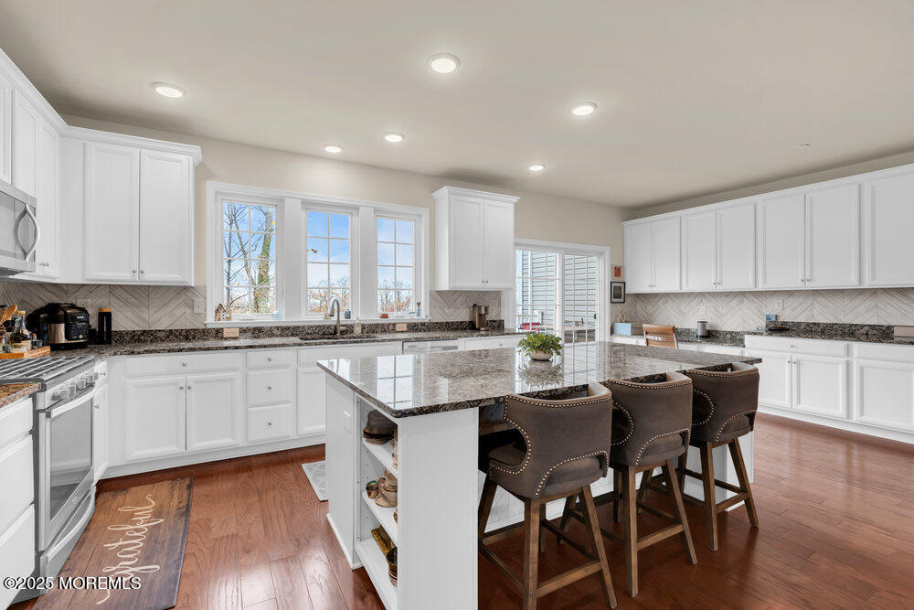 24 Lighthouse Point Road Highlands, NJ 07732 - Photo 30 of 63 a kitchen with a dining table chairs and white cabinets
