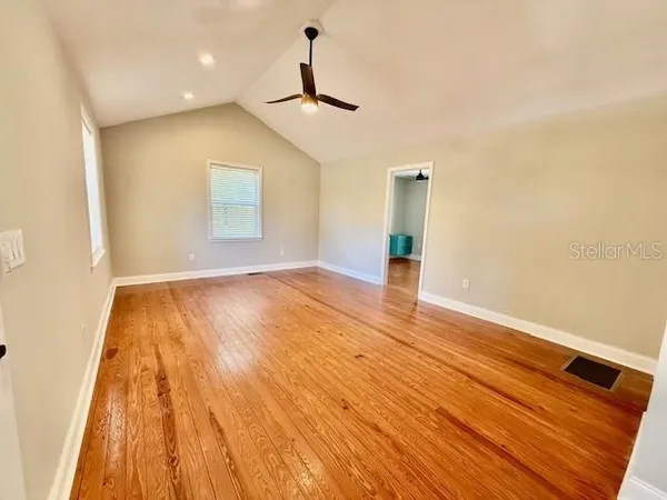 a view of empty room with wooden floor and ceiling fan