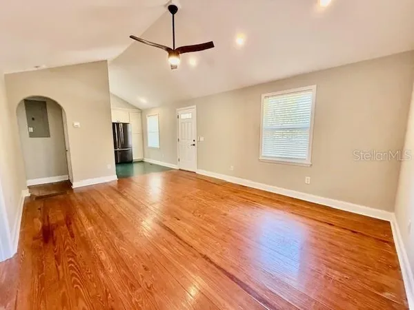 a view of an empty room with wooden floor and a window