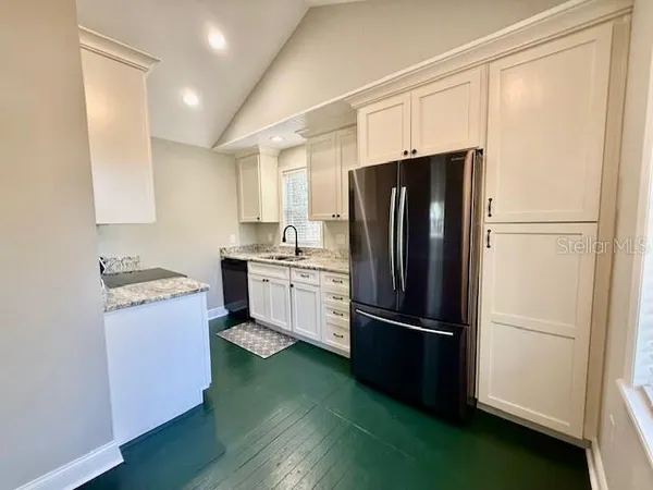 a kitchen with a refrigerator stainless steel appliances wooden floor and cabinets