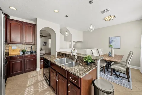 a kitchen with stainless steel appliances granite countertop a sink a stove and a wooden cabinets