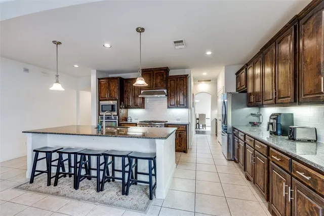a kitchen with stainless steel appliances granite countertop a stove refrigerator sink and cabinets