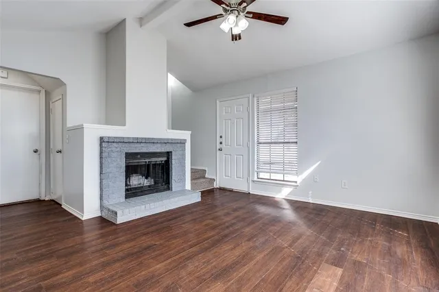 a view of an empty room with wooden floor fireplace and a window