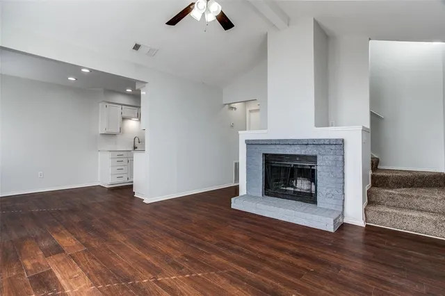 a view of an empty room with wooden floor fireplace and a window