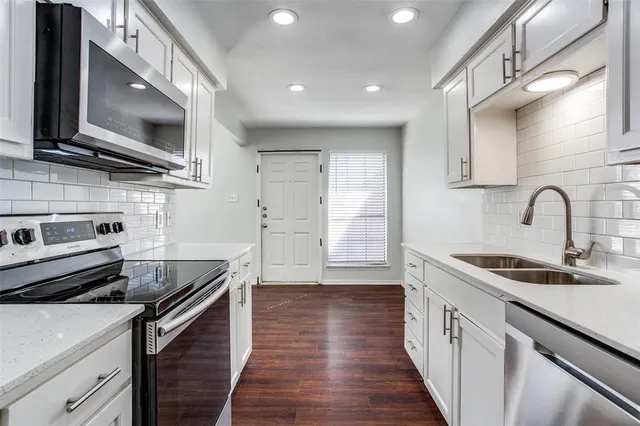 a kitchen with stainless steel appliances a sink dishwasher a stove top oven a refrigerator with wooden floor