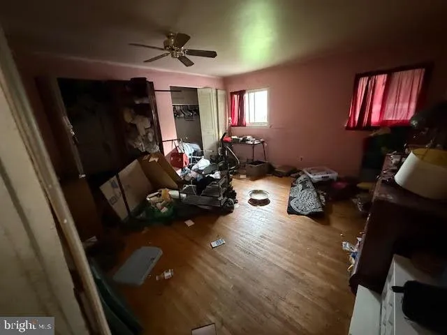 a living room with furniture hard wood floor and a ceiling fan