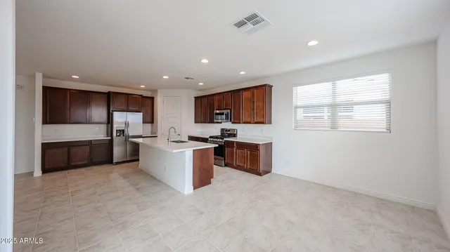 a large kitchen with stainless steel appliances granite countertop a stove a sink dishwasher a refrigerator and white cabinets with wooden floor