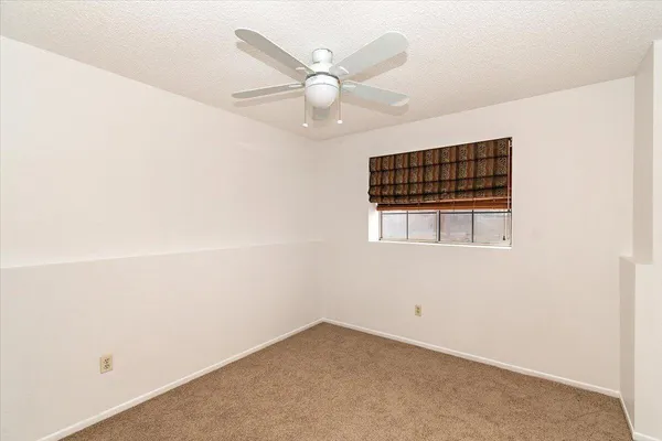 an empty room with a ceiling fan and window