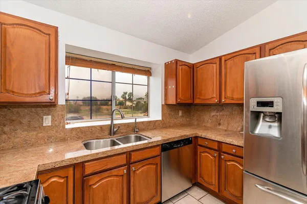 a kitchen with stainless steel appliances granite countertop a sink and a refrigerator