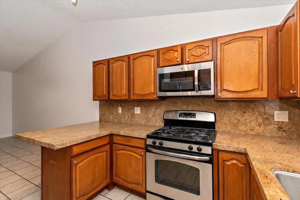 a kitchen with stainless steel appliances granite countertop wooden cabinets stove top oven and microwave