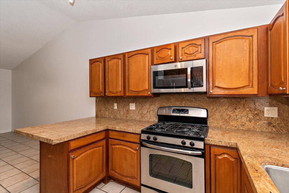 68954 Durango Road Cathedral City, CA 92234 - Photo 9 of 31 a kitchen with stainless steel appliances granite countertop wooden cabinets stove top oven and microwave