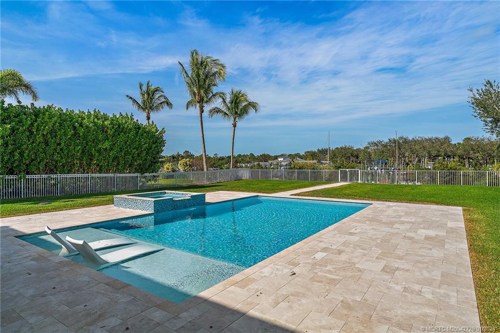 565 Southwest Yacht Basin Way Stuart, FL 34997 - Photo 40 of 55 a view of a swimming pool with a lounge chair and palm trees