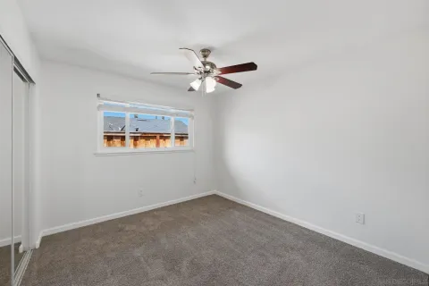 an empty room with a window and a ceiling fan
