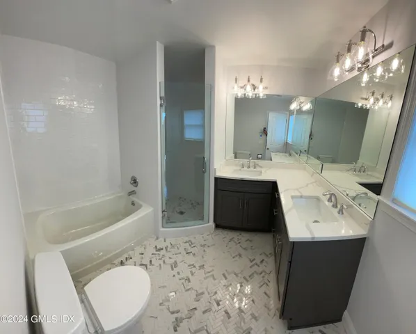 a bathroom with a sink a toilet a mirror and bathtub