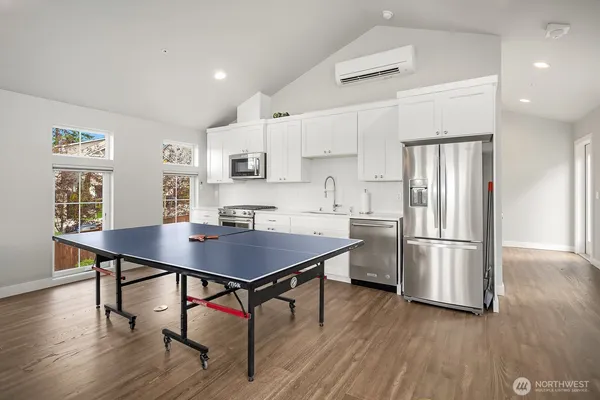 a kitchen with stainless steel appliances a table chairs wooden floors and white cabinets