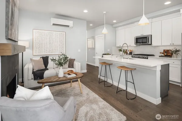 a living room with stainless steel appliances furniture a rug and a kitchen view