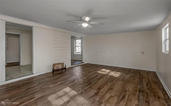 a view of empty room with wooden floor and fan