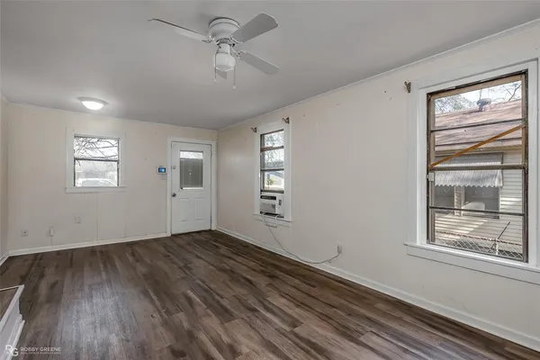 a view of empty room with wooden floor and fan