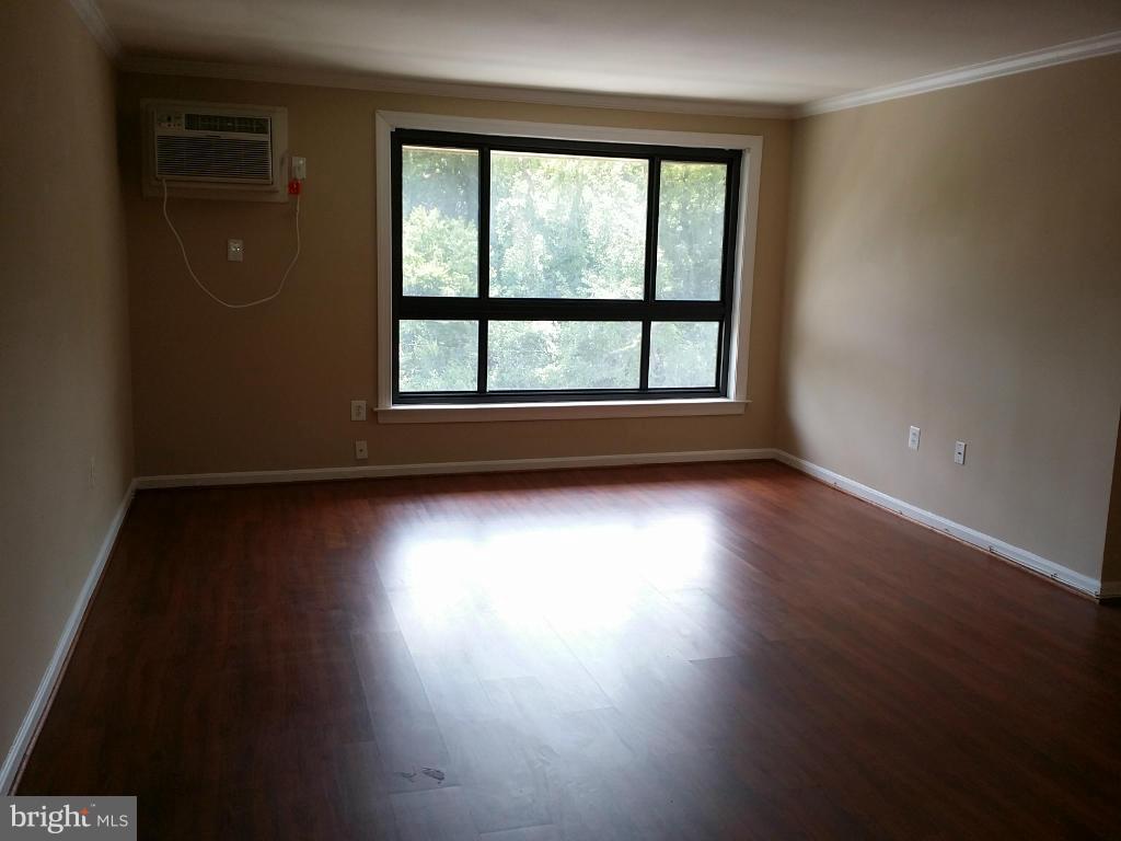 3105 Naylor Road Southeast, Unit 303 Washington, DC 20020 - Photo 3 of 10 an empty room with wooden floor and windows