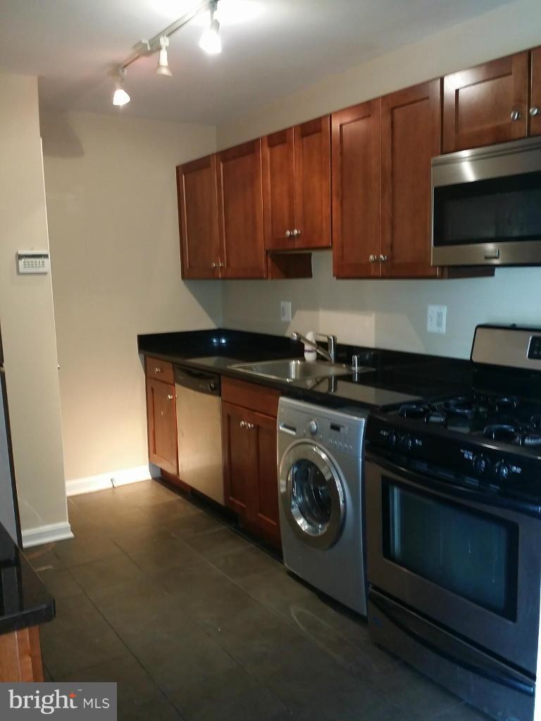 3105 Naylor Road Southeast, Unit 303 Washington, DC 20020 - Photo 5 of 10 a kitchen with stainless steel appliances granite countertop wooden cabinets and a stove top oven