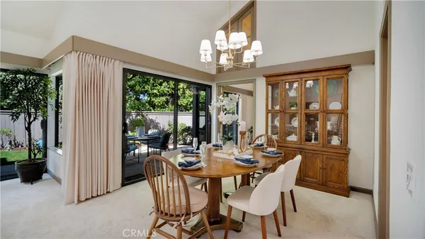 a dining room with wooden floor a chandelier a glass table and chairs