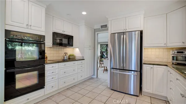 a kitchen with granite countertop white cabinets and stainless steel appliances