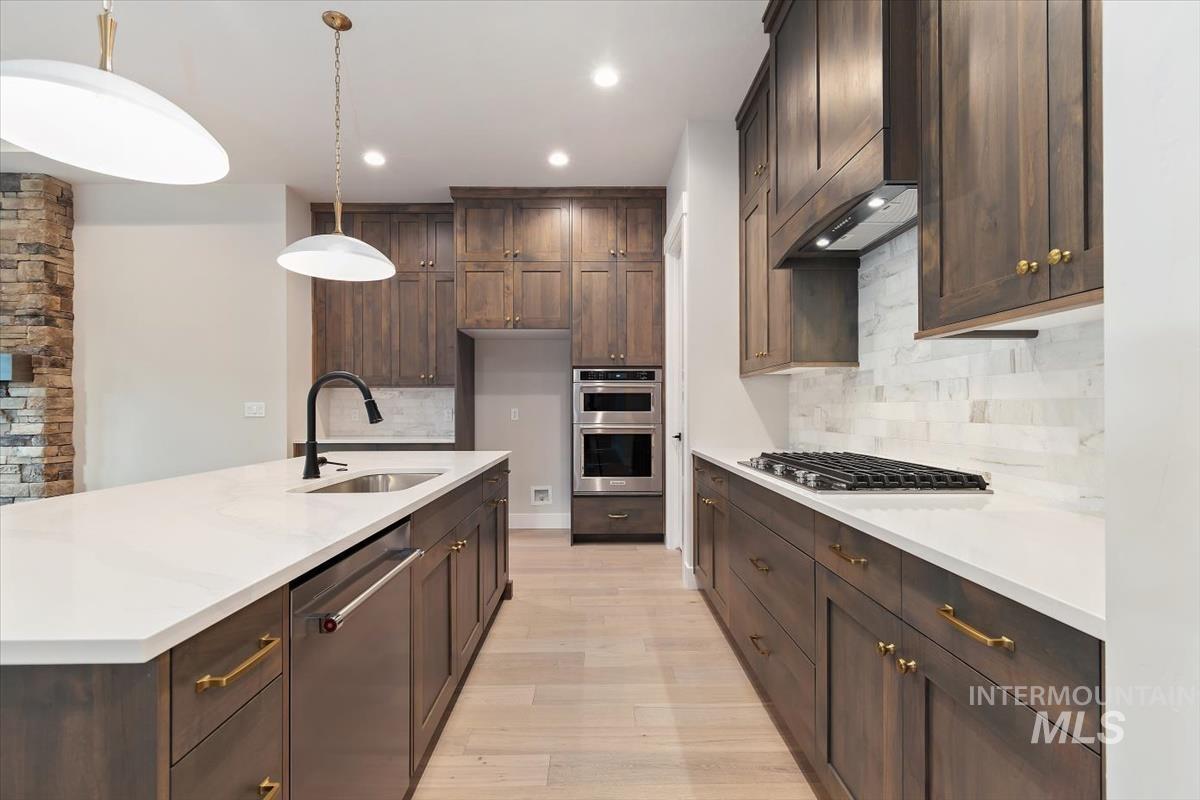2147 East Blakehurst Avenue Kuna, ID 83634 - Photo 11 of 43 Kitchen featuring dark brown cabinets, stainless steel appliances, tasteful backsplash, pendant lighting, and recessed lighting