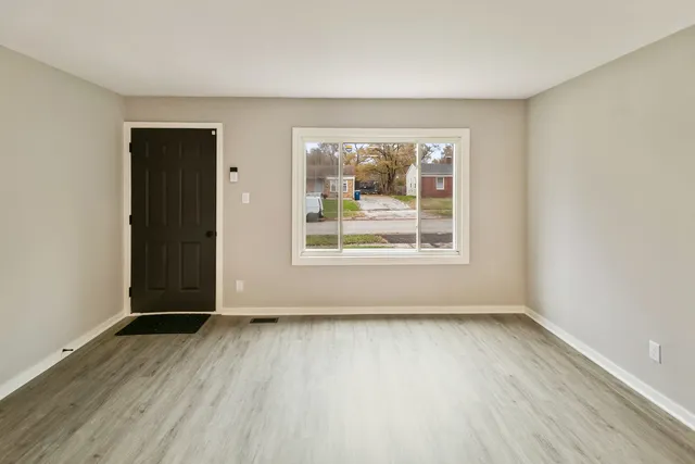 an empty room with wooden floor and windows