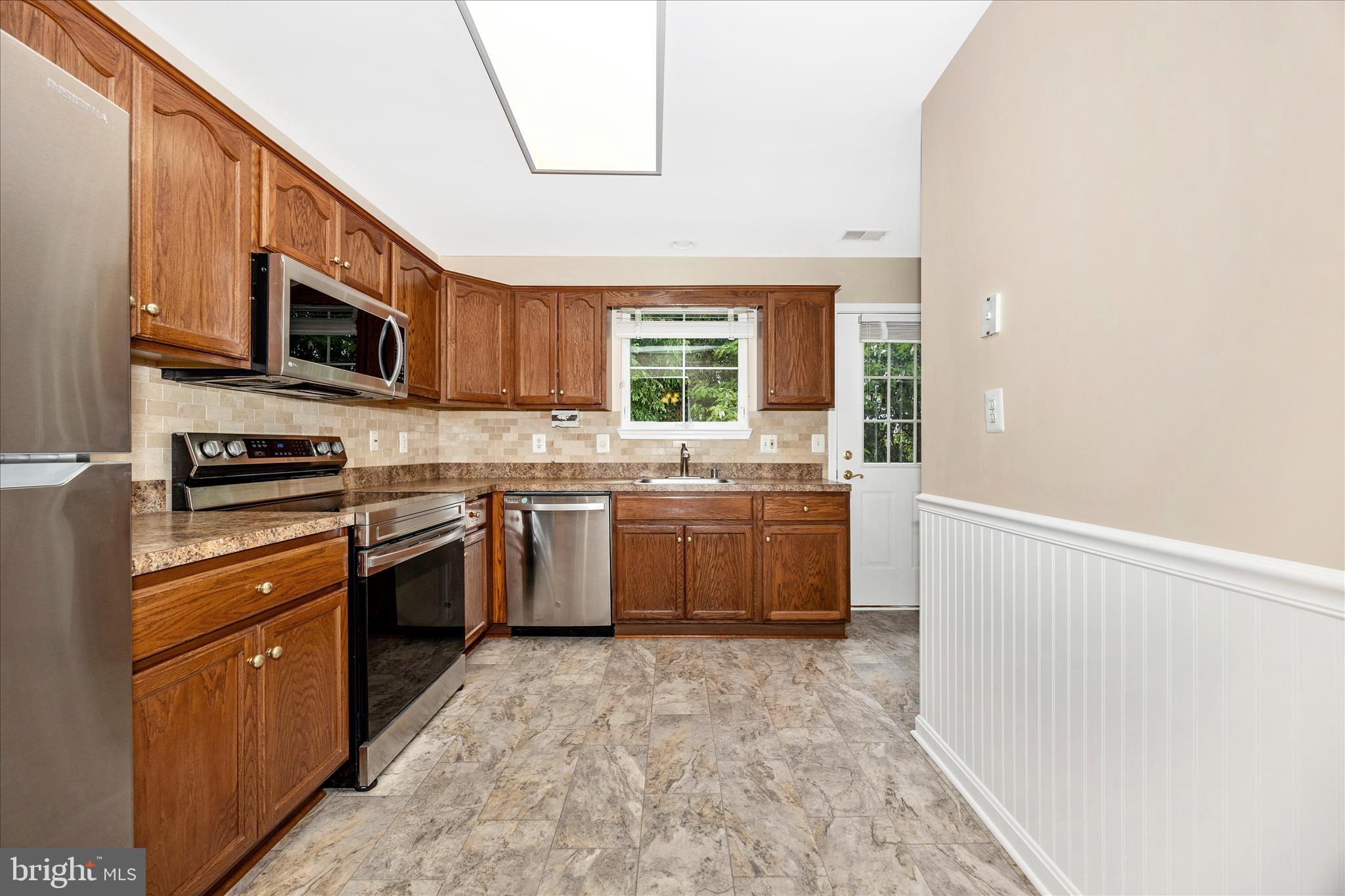 1007 Parade Lane Mount Airy, MD 21771 - Photo 18 of 55 a kitchen with stainless steel appliances kitchen island granite countertop a stove a sink and a microwave