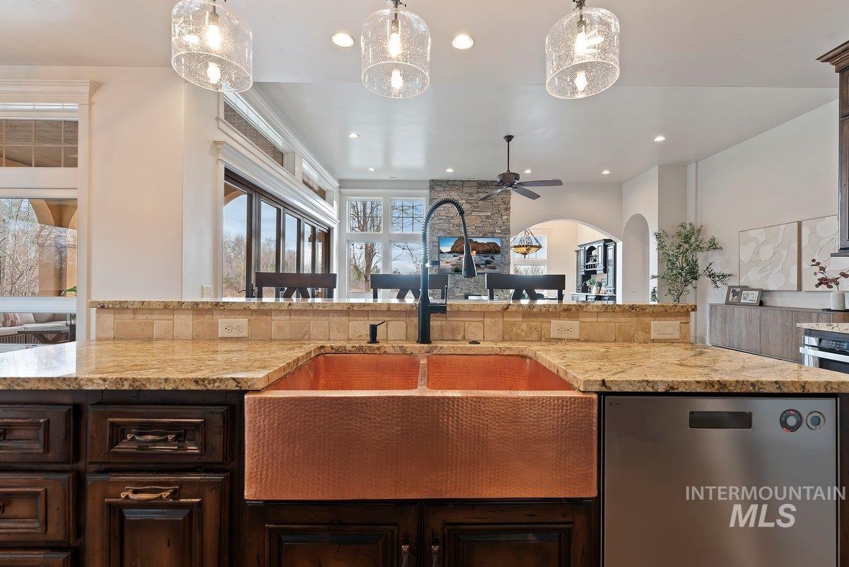 448 East Riversedge Lane Eagle, ID 83616 - Photo 12 of 50 Kitchen featuring dark brown cabinets, stainless steel appliances, light stone counters, hanging light fixtures, and ceiling fan