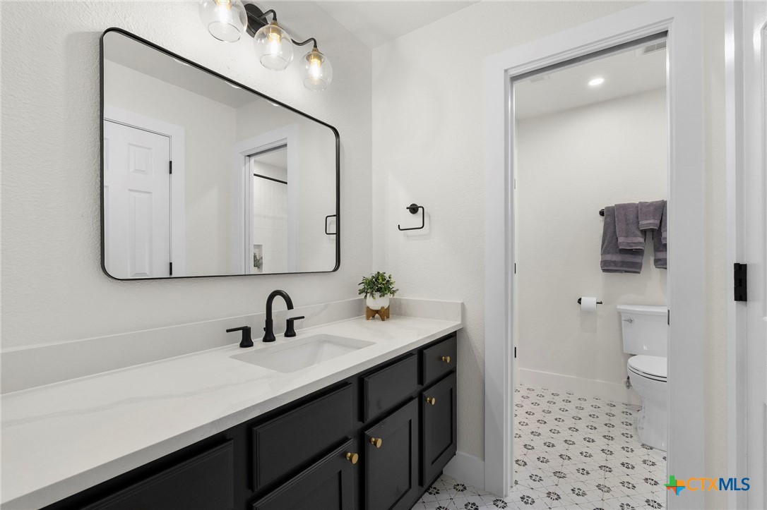 1130 Stoney Ridge Road Bulverde, TX 78163 - Photo 28 of 42 a bathroom with a sink a toilet and a mirror