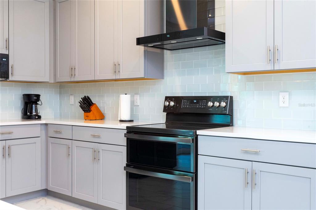 445 Strand Drive Melbourne Beach, FL 32951 - Photo 16 of 99 a kitchen with white cabinets and black appliances