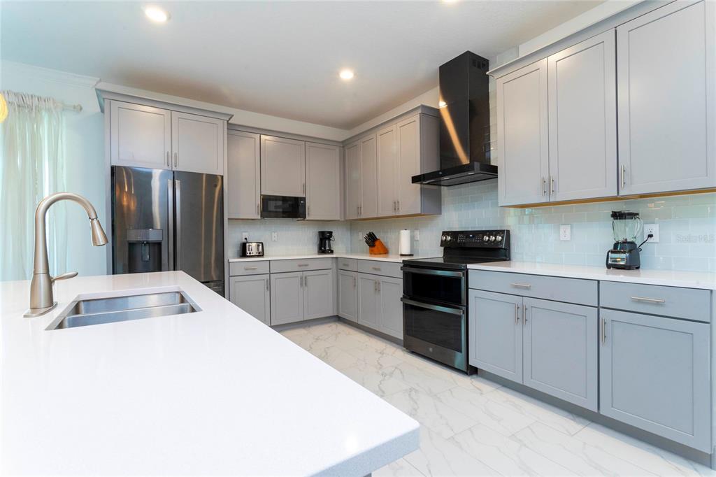 445 Strand Drive Melbourne Beach, FL 32951 - Photo 17 of 99 a kitchen with stainless steel appliances a refrigerator sink and cabinets