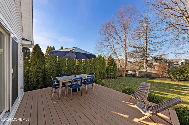 a view of a patio with table and chairs under an umbrella with wooden floor
