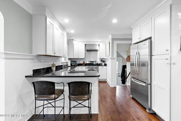 a kitchen with stainless steel appliances granite countertop a dining table chairs refrigerator and sink