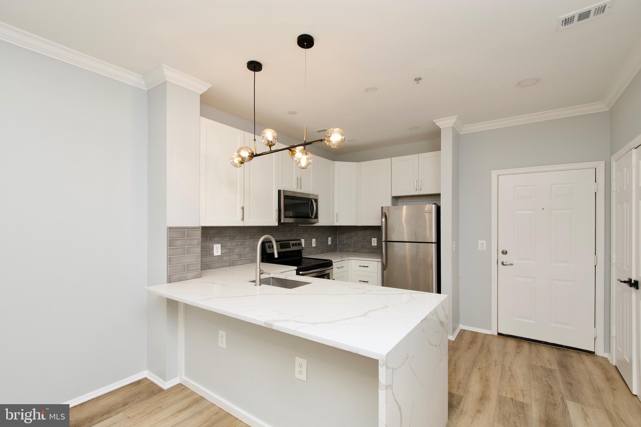 3003 Nicosh Circle, Unit 3106 Falls Church, VA 22042 - Photo 4 of 25 a kitchen with kitchen island a sink stainless steel appliances and wooden floor