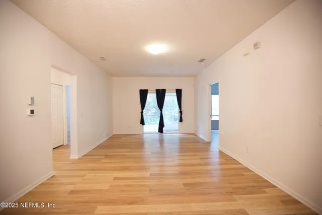 a view of an empty room with window and wooden floor