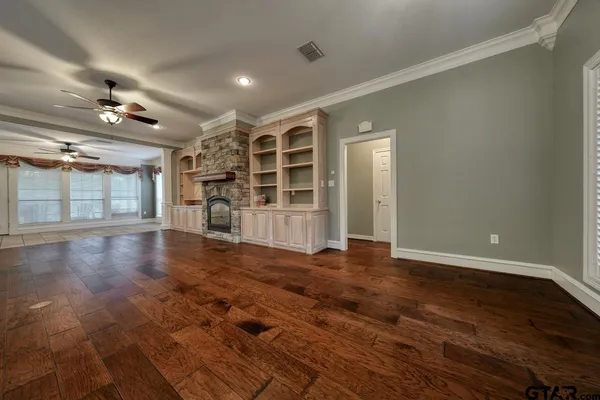 a view of a livingroom with a ceiling fan wooden floor and a ceiling fan