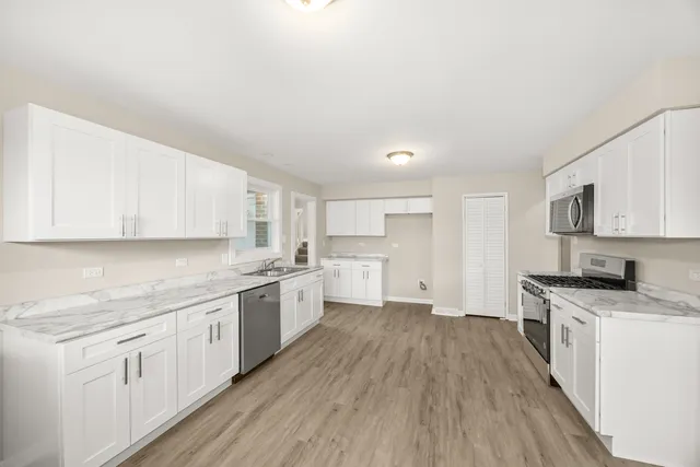 a kitchen with a sink wooden floor and stainless steel appliances