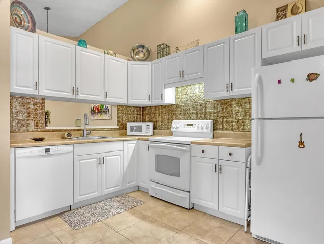 a kitchen with granite countertop white cabinets and white appliances